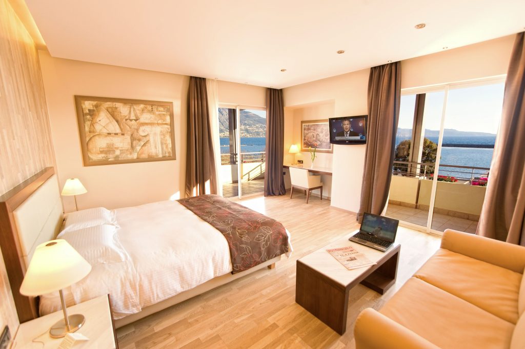 Enjoy a comfortable stay with a large bed, desk, and sofa, offering a view of the sea and mountains at Pharae Palace.